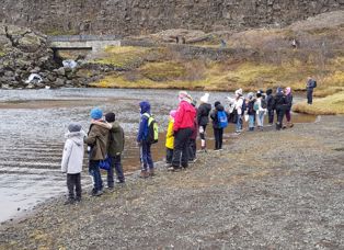 Skólabörn standa í röð við bakka öxarár í prestakróki