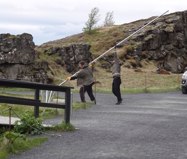 Tveir landverði lyfta fánastöng í fánaborg við Hamraskarð hjá Lögbergi. Landvarðajeppi til hægri